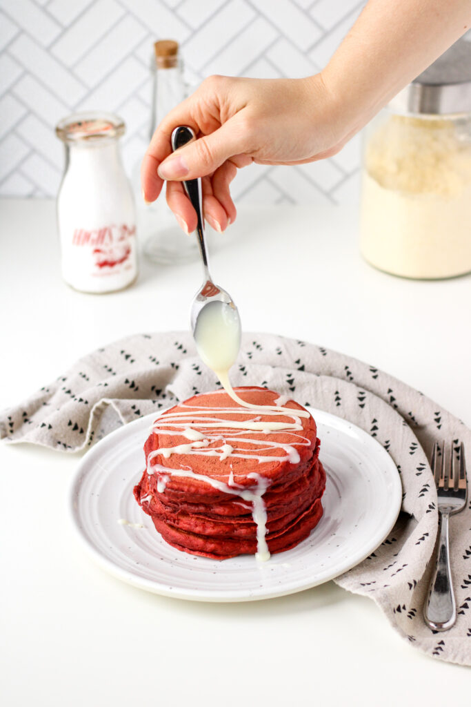 Drizzling white chocolate on Red Velvet Pancakes