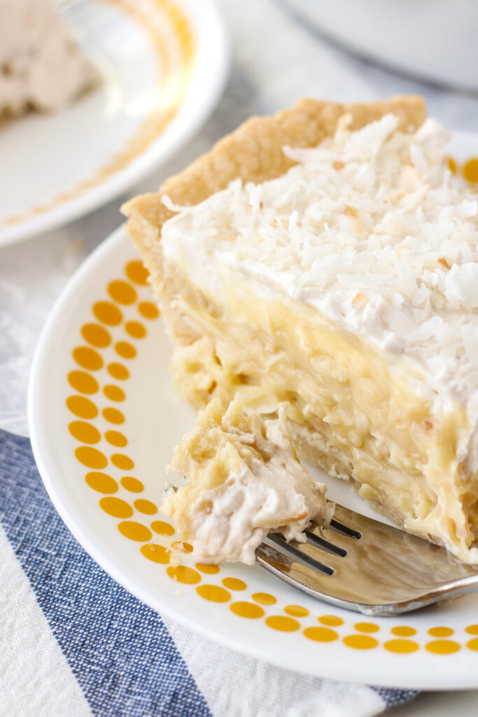 Coconut Cream Pie on a plate with a bite on a fork