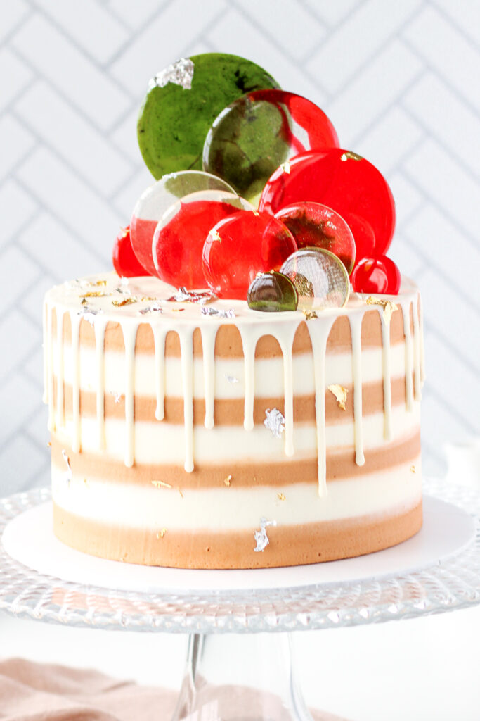 Eggnog Cake with buttercream stripes, eggnog drip, and isomalt discs