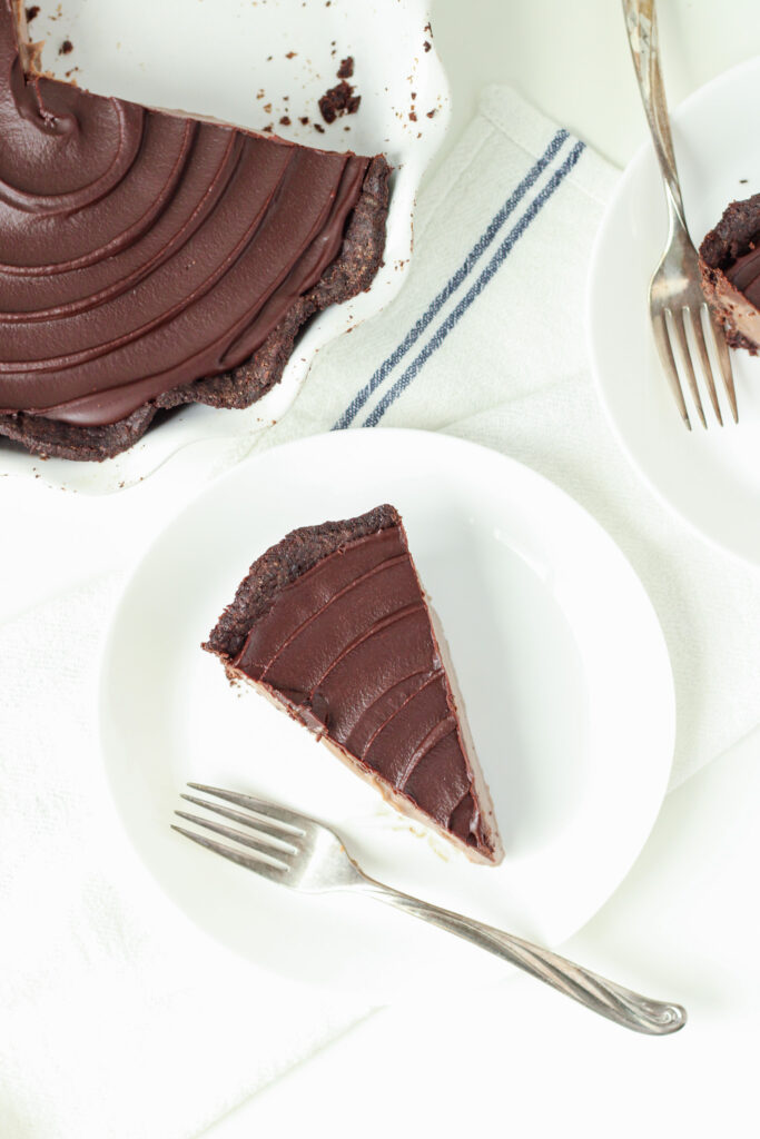 A slice of Chocolate Coffee Pie on a plate with the rest of the pie in the background