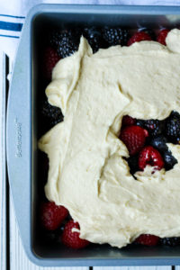 Adding cake batter to the berries