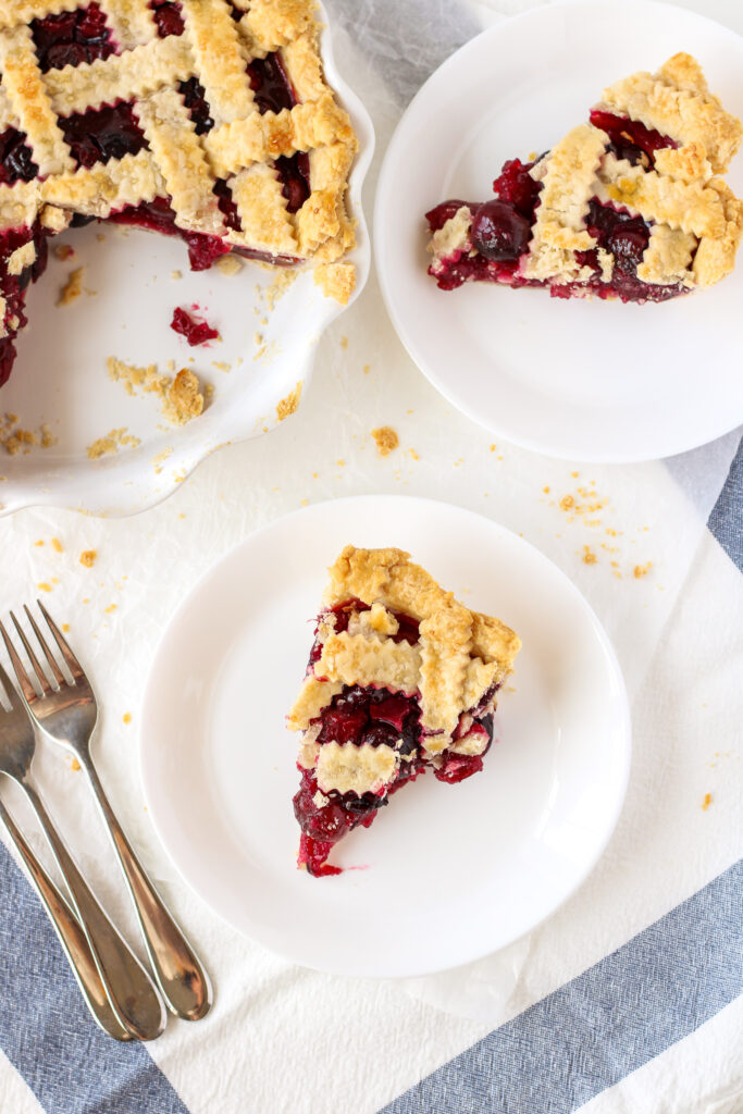 Sliced cherry pie on plates with forks