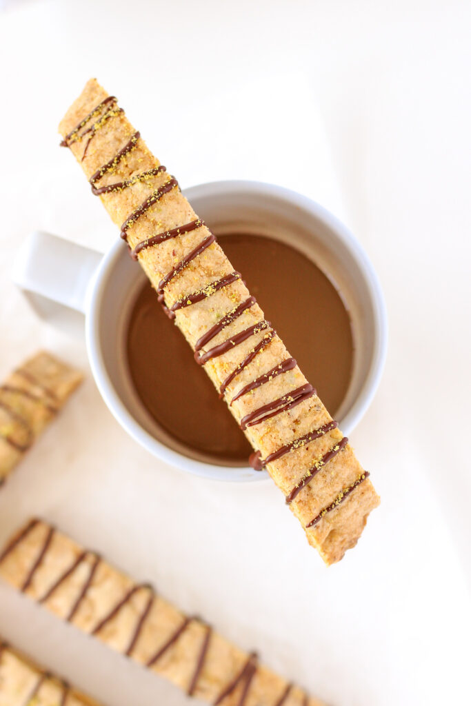 Brown Butter Pistachio Biscotti sitting on a mug of coffee