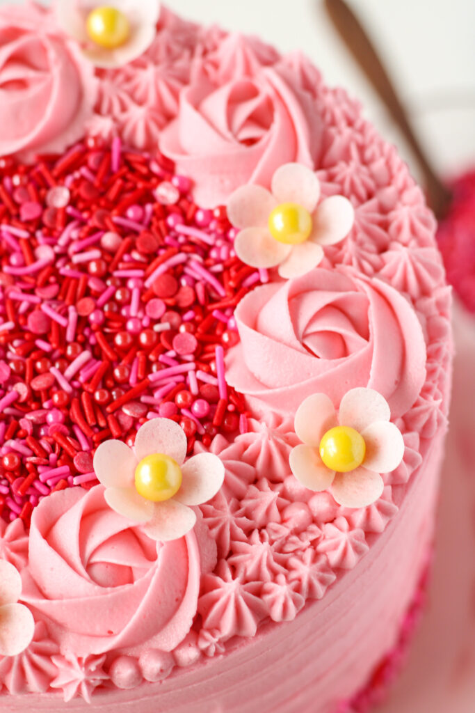 wafer paper strawberry blossoms on a pink cake with sprinkles