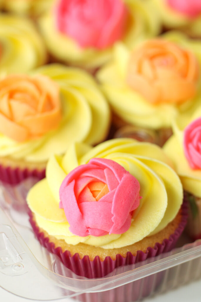 Cupcakes with yellow frosting and pink and orange buttercream flowers