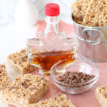 Rice Krispie Treats with a bottle of maple syrup shaped like a maple leaf, and a small bowl of cinnamon sweet bits
