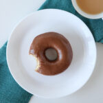 A Nutella Donut on a white plate with a cup of tea next to it.