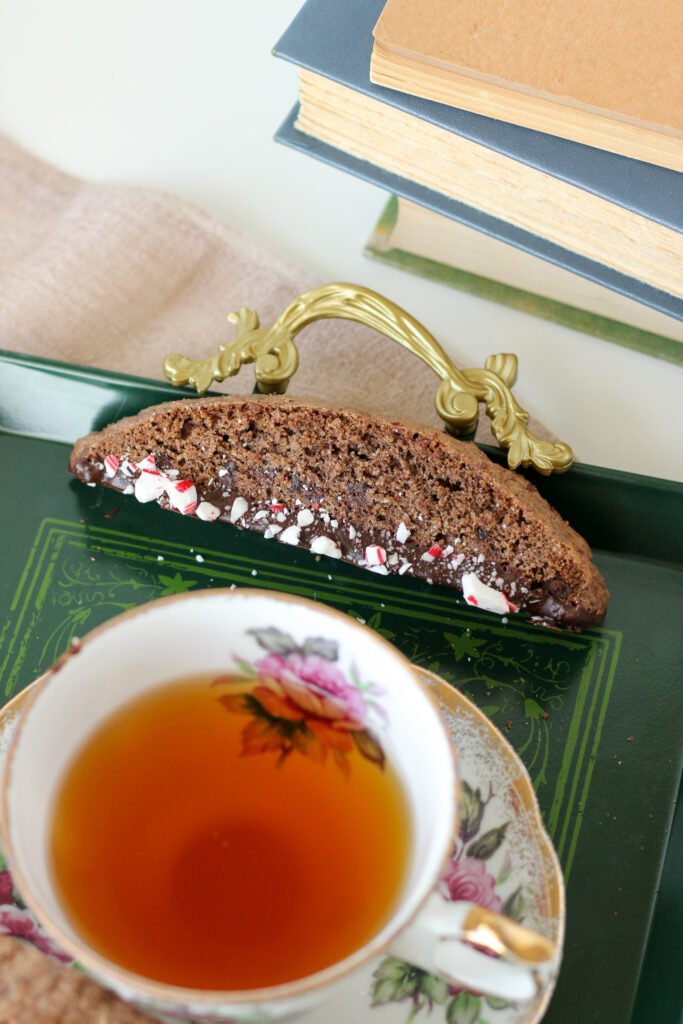 Chocolate Peppermint Biscotti on a green serving tray between a cup of tea and a stack of books