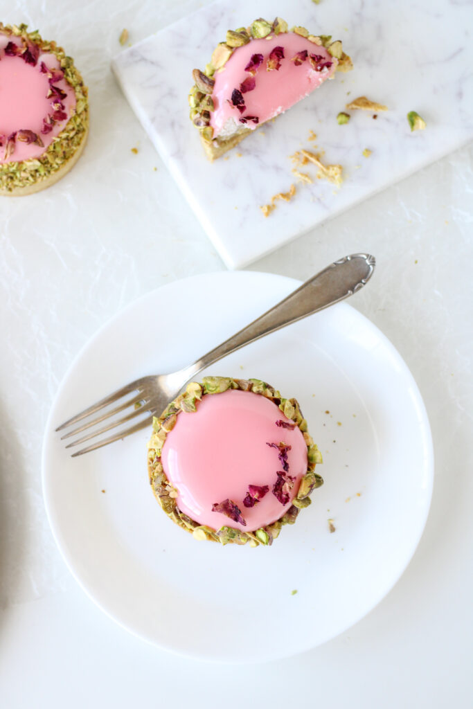 Pistachio, Rose, and Strawberry Tartlet on a plate with a fork