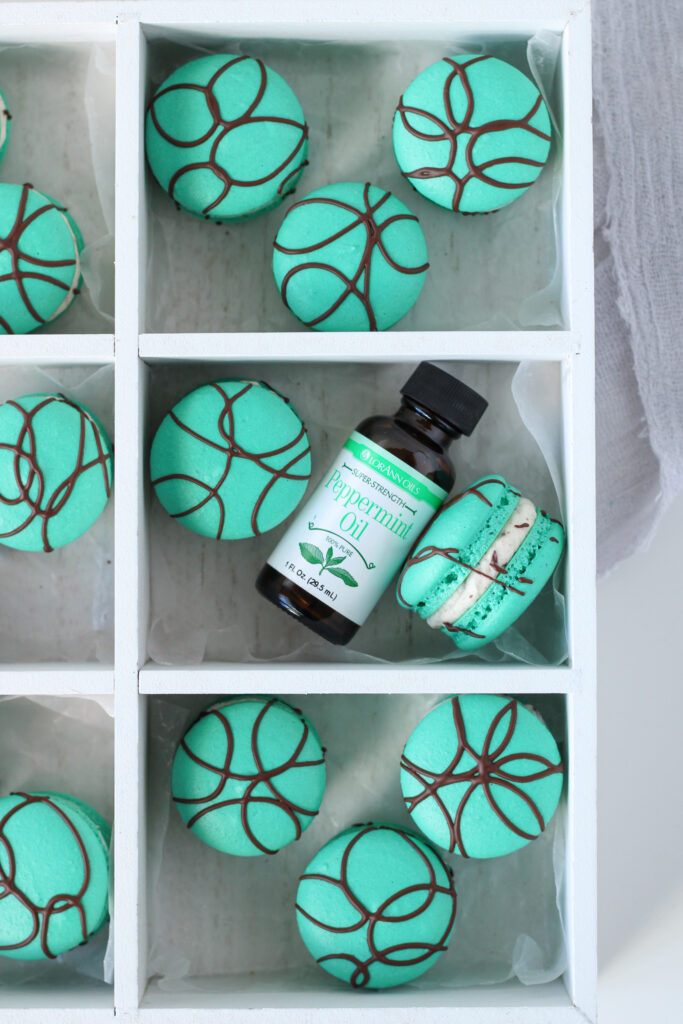 Peppermint Chip Macarons in a box with a bottle of peppermint oil