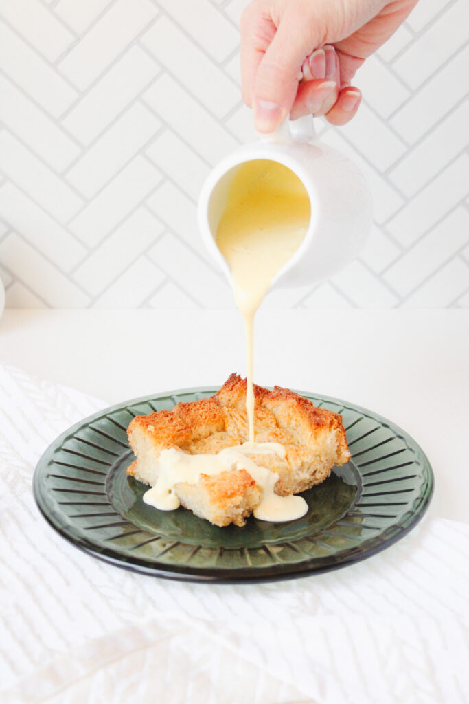 Pouring creme anglaise on a slice of bread pudding